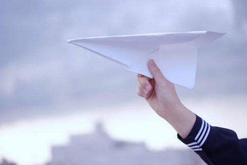 紙飛行機を飛ばしている女子高生