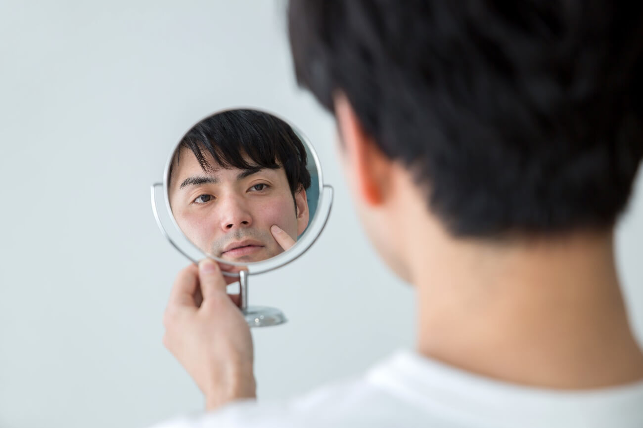 手鏡で自分の顔を眺める男性